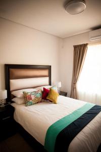 1 dormitorio con 1 cama grande y almohadas coloridas en Apartments @ 125, en Gaborone