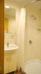 a bathroom with a sink and a shower with a shower curtain at Causeway Bay Inn (@Percival Street) in Hong Kong