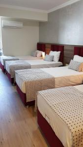 a group of four beds in a room at Laleli Hotel Izmir in Izmir