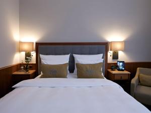 ein Schlafzimmer mit einem großen weißen Bett und einem Stuhl in der Unterkunft Platzl Hotel - Superior in München