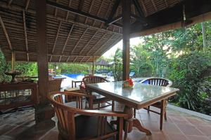 een eetkamer met een tafel en stoelen en een zwembad bij Nara Ubud Cottage by Mahaputra in Ubud