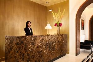 a woman standing behind a counter in a lobby at Margutta 19 - Small Luxury Hotels of the World in Rome