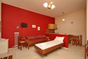 Habitación con cama y pared roja. en Hotel Marialena en Ancient Epidavros