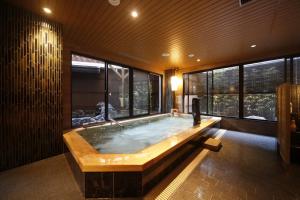 a large bath tub in a room with windows at Onyado Nono Nara Natural Hot Spring in Nara