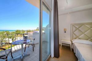 een kamer met een balkon, een bed en een tafel bij Hotel Corona Beach Peschici in Peschici