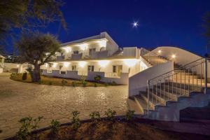 a large white house with a staircase at night at Hotel Corona Beach Peschici in Peschici