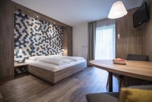 アンドリアーノにあるHotel Garni Andrianerhofのベッドとテーブルが備わるホテルルームです。