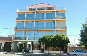 a large building with a car parked in front of it at Hotel Fantilli in Puerto Madryn
