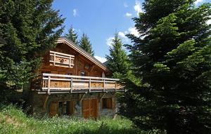 a large wooden house with a balcony in the woods at Odalys Chalet Les Alpages in Les Deux Alpes
