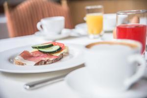 einen Teller mit einem Sandwich auf dem Tisch mit einem Glas Orangensaft in der Unterkunft Hotel Garni Andrianerhof in Andrian