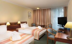 Una habitación de hotel con dos camas y un televisor. en Wyndham Garden Kassel, en Kassel