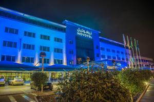 un bâtiment bleu avec un panneau sur lui la nuit dans l'établissement Novotel Yanbu Albahr, à Yanbu