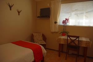 a bedroom with a bed and a table and a window at Easy Five Guest House in Somerset West