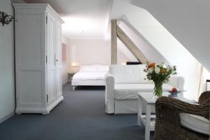 ein weißes Schlafzimmer mit einem weißen Bett und einem Tisch in der Unterkunft Hotel Hirschen am See in Meilen