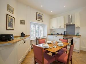 a kitchen with a wooden table and chairs and a kitchen with white cabinets at Castle Gatehouse in Winchcombe
