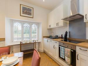 eine Küche mit weißen Schränken, einem Tisch und einem Esszimmer in der Unterkunft Castle Gatehouse in Winchcombe