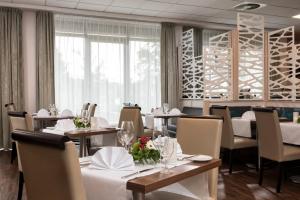 a dining room with tables and chairs and a window at Wyndham Garden Kassel in Kassel