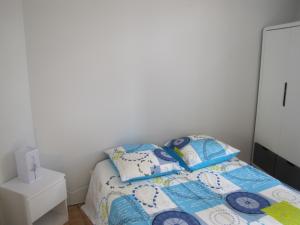 a bedroom with a bed with blue and white pillows at Appartement de charme à la montagne in Ax-les-Thermes