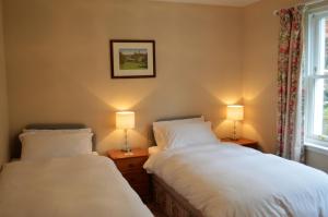 Teal Cottage في Clachan of Glendaruel: سريرين في غرفة بها مصباحين