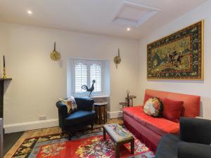 a living room with a red couch and a chair at Castle Gatehouse in Winchcombe +17 photos