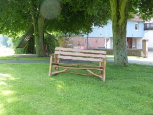 un banco de madera sentado en el césped bajo dos árboles en Ferienwohnungen Zur Mühle, en Mossautal