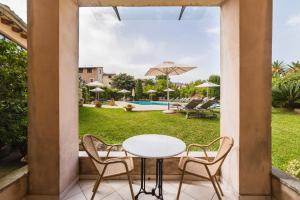 un patio con mesa, sillas y piscina en Hotel Ca'l Bisbe, en Sóller