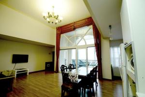 a dining room with a table and chairs and a television at Jennyville Pension in Seogwipo