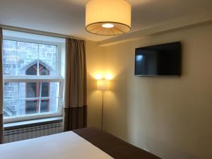 a bedroom with a bed and a tv and a window at The Coffee House Hotel in Aberdeen
