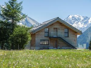 ein Haus auf einem Feld mit Bergen im Hintergrund in der Unterkunft Chalet Avista in Rosswald