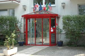 une cabine de téléphone rouge devant un bâtiment arborant des drapeaux dans l'établissement Hotel Roemerstein, à Mayence