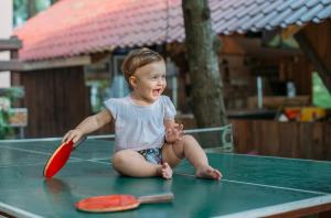 a baby sitting on a table playing with a red paddle at Hotel Forest Fairy in Shekvetili