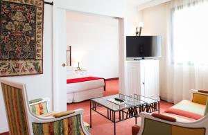 Habitación de hotel con cama, mesa y sillas en Avignon Grand Hotel, en Aviñón