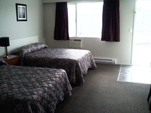 um quarto de hotel com duas camas e uma janela em Caravan INN em Quesnel