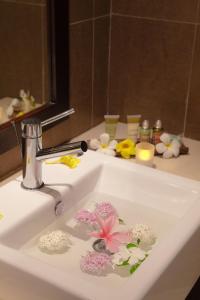 a bathroom sink with a faucet with flowers in it at Ocean Villas Hotel in Grand Baie