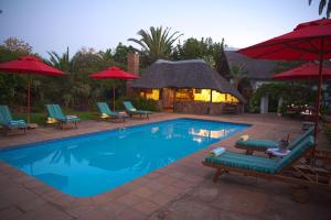 a swimming pool with lounge chairs and umbrellas at Easy Five Guest House in Somerset West