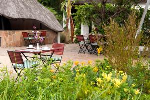 a patio with a table and chairs in a garden at Easy Five Guest House in Somerset West