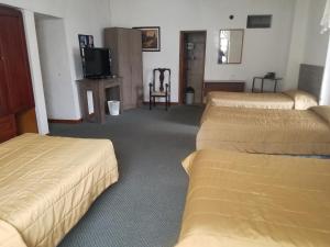 ein Hotelzimmer mit drei Betten und einem Fernseher in der Unterkunft Hostal Chordeleg in Cuenca