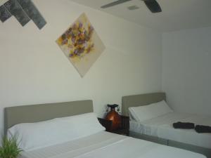 a bedroom with two beds and a painting on the wall at Hotel Paka INN in Paka