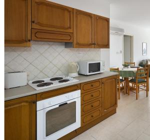 a kitchen with wooden cabinets and a white stove top oven at Club Aphrodite in Erimi