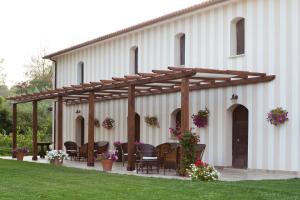 a pergola on a white building with chairs and flowers at Agriturismo La Pesca in Broccostella