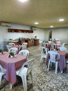 Torre do Sol Park Hotel في Chapadinha: غرفة مع طاولات وكراسي بيضاء مع مفارش مائدة وردية وأرجوانية