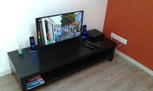 einen Flachbild-TV auf einem schwarzen Tisch in der Unterkunft Appartements T2 Proche de Rennes in Chantepie