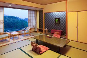 ein Wohnzimmer mit einem Tisch und einem großen Fenster in der Unterkunft Izu-Nagaoka Hotel Tenbo in Izunokuni