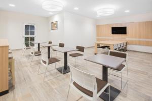 a waiting room with tables and chairs and a flat screen tv at Microtel Inn & Suites by Wyndham Cuauhtemoc Campos Menonitas in San Antonio