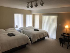 two beds in a bedroom with windows and two lamps at Emperial Suites in North Vancouver