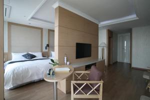 a bedroom with a bed and a desk and a tv at Benikea Hotel Yeosu in Yeosu