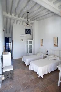 two beds in a room with white walls and tile floors at Hotel Rural Hoyo Bautista in Martín de la Jara