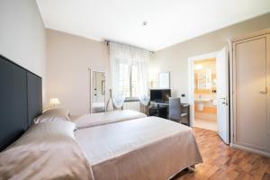 una camera d'albergo con 2 letti e una scrivania di Hotel Bernardino a Lucca