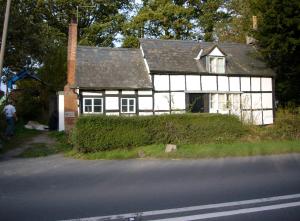 une maison blanche et noire sur le côté d'une route dans l'établissement Chestnut Cottage, à Eardisley