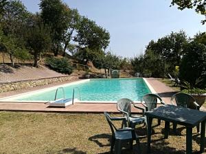 a swimming pool with chairs and a table next to it at Agriturismo La Manonera in Montepulciano